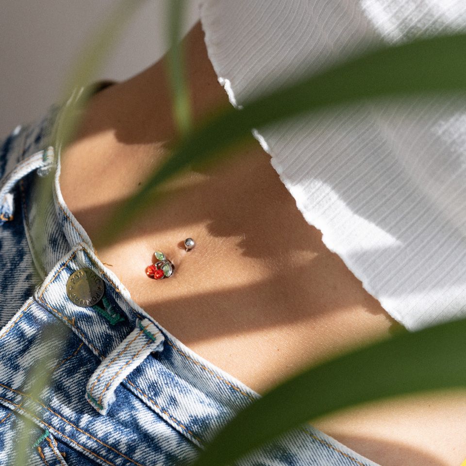 Umbigo piercing com uma cereja vermelha